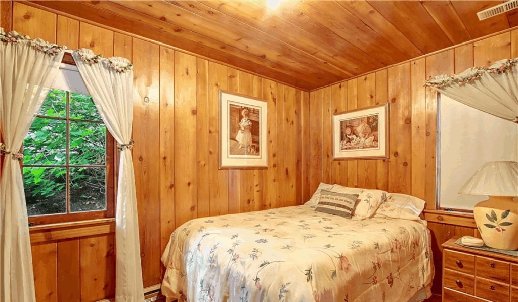 Rustic bedroom with wood-paneled walls, soft lighting, and a cozy atmosphere